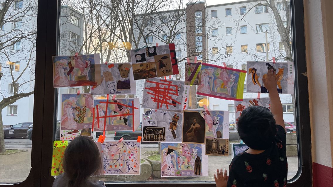Kinder vor einem großen Fenster mit Bildern