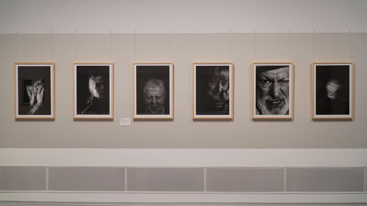 Foto: Sechs Foto-Porträts an einer Wand.