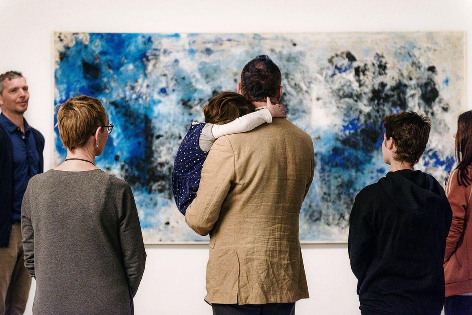 Foto: Erwachsene und ein Kind während einer Führung stehen vor einem Gemälde.
