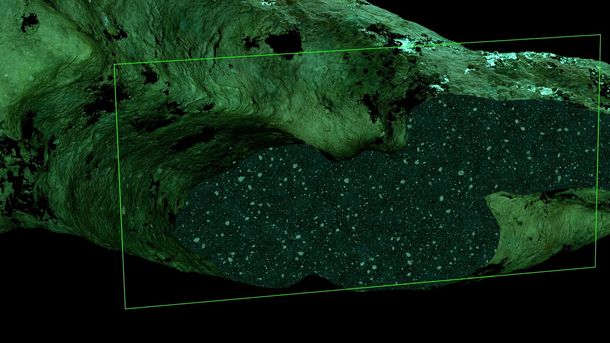 Rock surface in shades of green in which a rectangular area is highlighted with a translucent green frame. The highlighted area shows a dense structure with small, scattered dots that look like rock fragments or sediment particles.