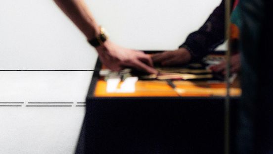 Foto: Kunstwerk an der Wand, davor betasten zwei Menschen das dazugehörige Tastmodell.