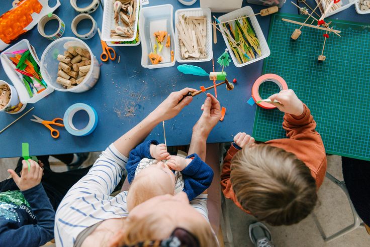 Photo: Adult and two children doing handicrafts together at a table.