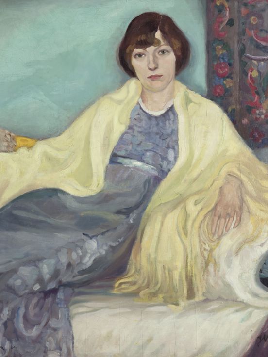 Gemälde einer Frau, die auf einem Sofa sitzt. Sie trägt ein fließendes blaues Kleid und ein gelbes Tuch über den Schultern. Der Hintergrund ist türkisfarben, und um sie herum liegen gemusterte Kissen und Teppiche.