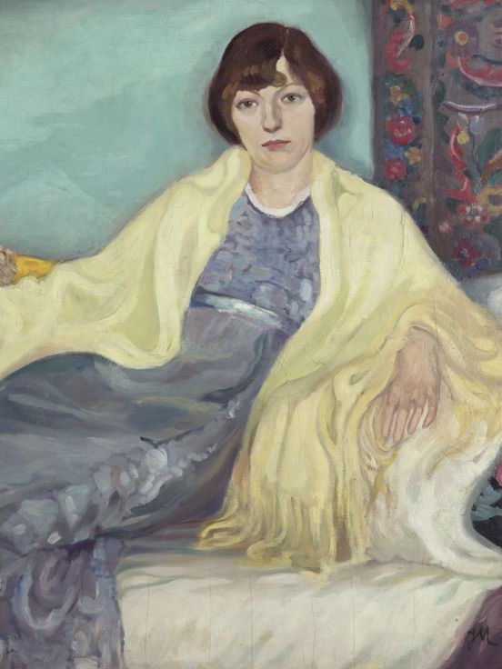 Gemälde einer Frau, die auf einem Sofa sitzt. Sie trägt ein fließendes blaues Kleid und ein gelbes Tuch über den Schultern. Der Hintergrund ist türkisfarben, und um sie herum liegen gemusterte Kissen und Teppiche.