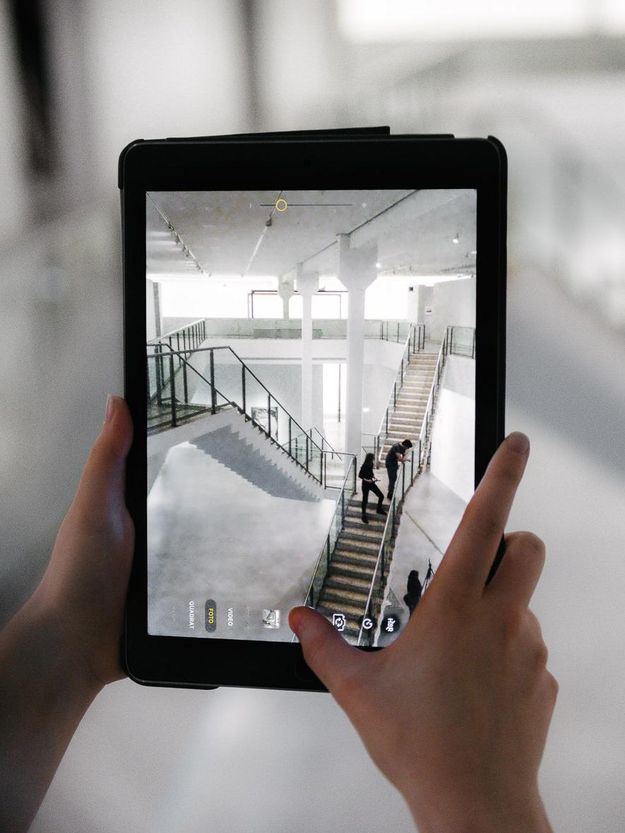Foto: Person hält ein Tablet in der Hand. Es zeigt die Aufnahme eines Fotos von der Treppe im Museum.