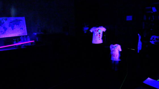 Foto: In einem dunklen Raum sind nur helle T-Shirts von Schwarzlicht beleuchtet.