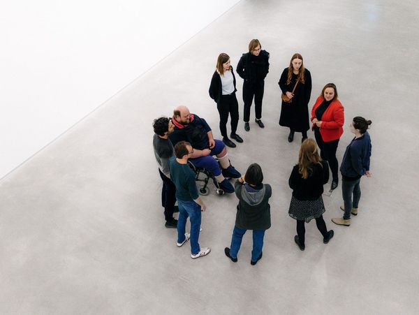 Foto: Bei einer Führung sind Menschen mit und ohne Rollstuhl in einem Kreis versammelt.