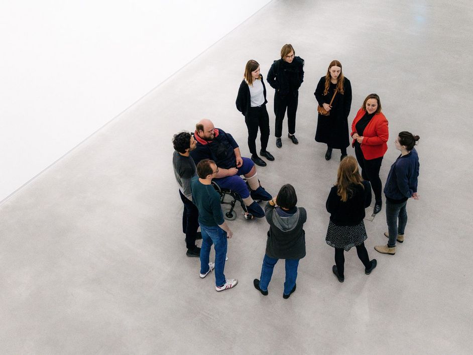 Photo: People with and without wheelchairs are gathered in a circle during a guided tour.