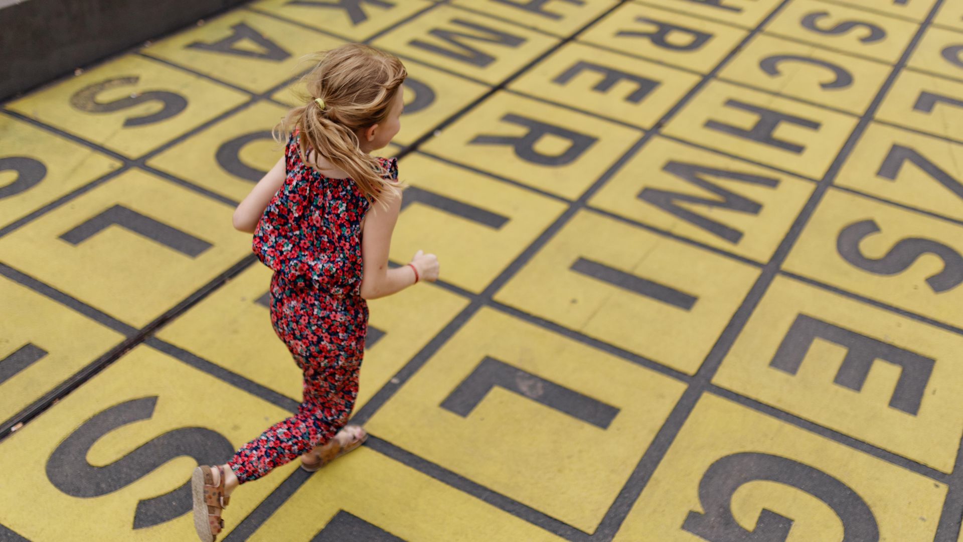 Kind rennt über Buchstabenfeld