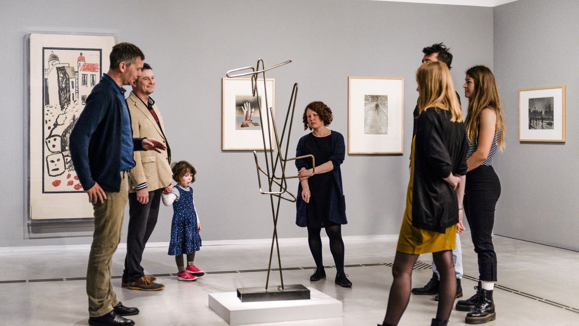 Photo: Adults and a child during a guided tour. They are standing around a sculpture.
