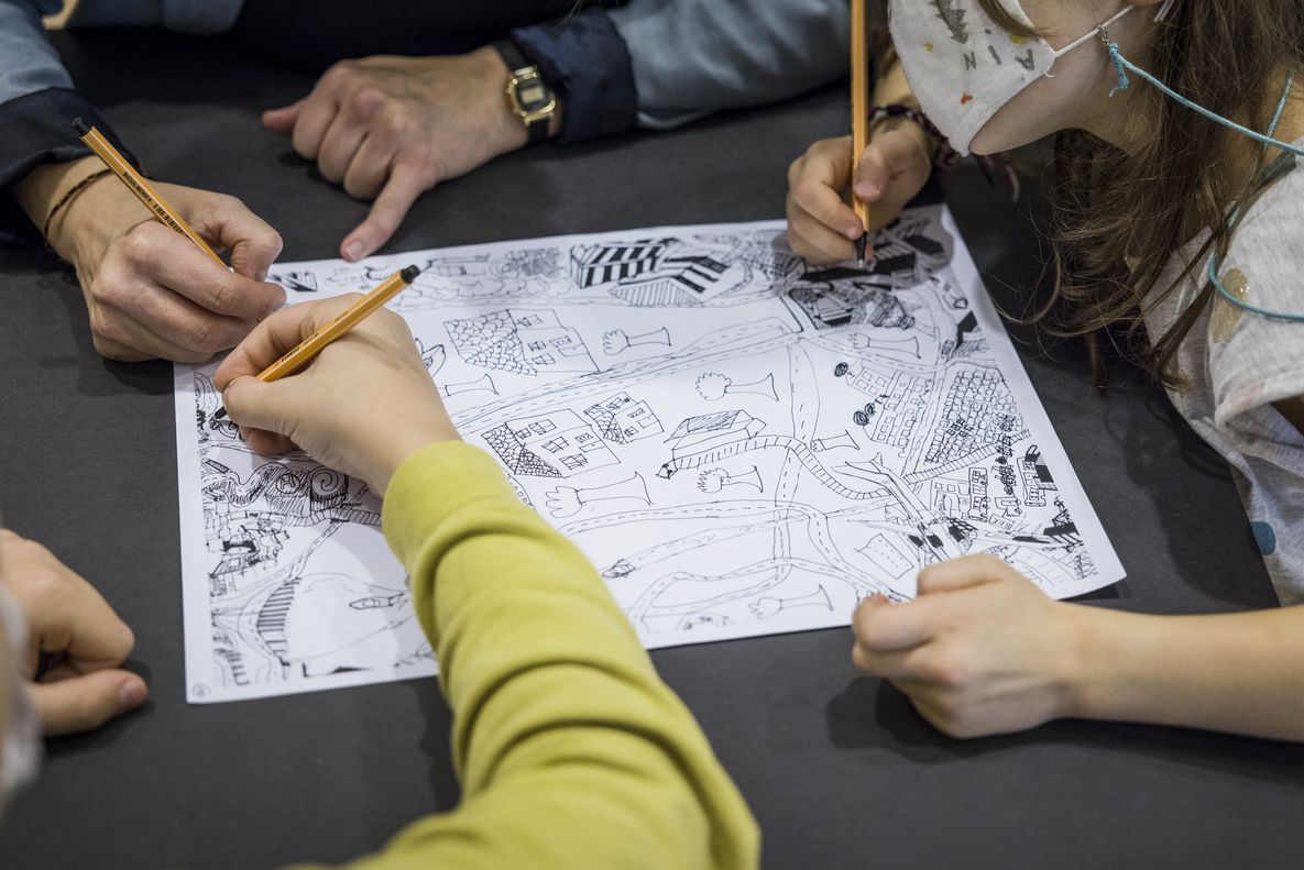 Foto: Drei Paar Kinderhände zeichnen zusammen auf einem Blatt Papier