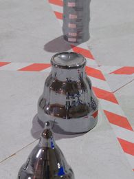 Filmstill: Verschiedene Metallformen stehen auf dem Boden, der durch Absperrmarkierungen unterteilt wird