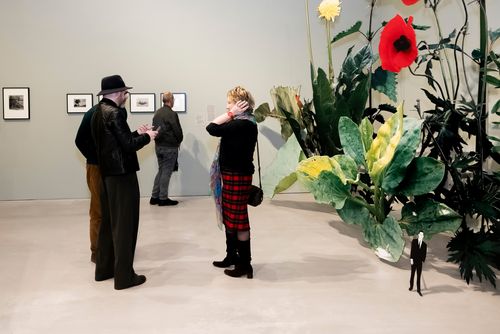 Foto: Blick in den Ausstellungsraum von „Closer to Nature“, in dem vier Personen neben einer großen Pflanzen-Installation zu sehen sind.