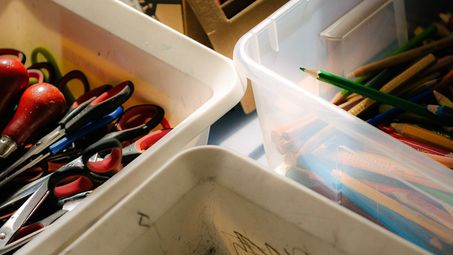 Foto: Kisten mit Buntstiften, Bleistiften, Scheren und bunten Klebebändern.