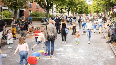 Foto: Blick auf die temporäre Spielstraße in der Alten Jakobstraße mit vielen Kindern und einigen Erwachsenen.