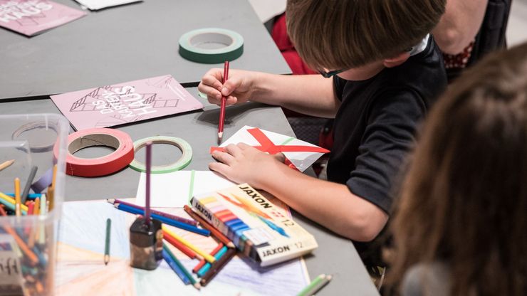 Foto: Eine erwachsene Person und Kinder sitzen an einem Tisch und basteln.