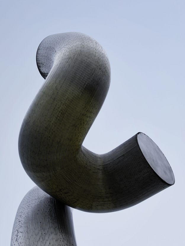 Photo: Part of a sculpture made of silver metal against a blue sky 