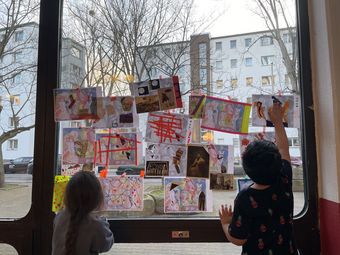 Kinder vor einem großen Fenster mit Bildern