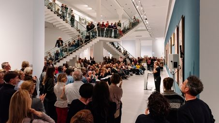 Photo: Scenes from the opening night, showing people either listening to the opening speeches in the staircase hall of the Berlinische Galerie or in the exhibition rooms.