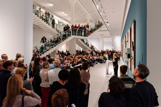 Photo: Scenes from the opening night, showing people either listening to the opening speeches in the staircase hall of the Berlinische Galerie or in the exhibition rooms.