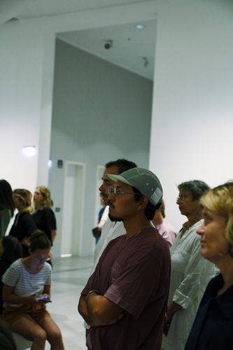 People are standing in the exhibition space, listening to a conversation.