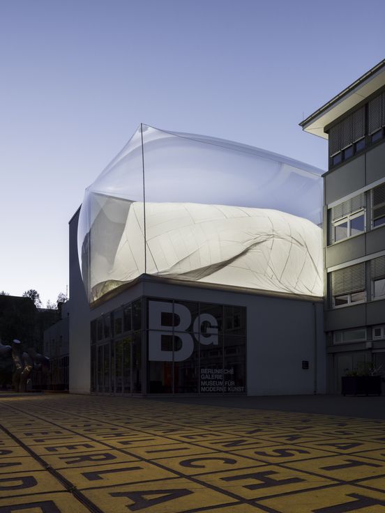 Exterior view of the Berlinische Galerie at dusk, featuring a striking installation on the roof.