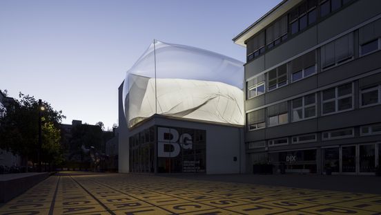 Exterior view of the Berlinische Galerie at dusk, featuring a striking installation on the roof.