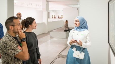 Eine Schülerin spricht während der Kunstgespräche mit zwei Besucher*innen. Sie steht in der Dauerausstellung der Berlinischen Galerie. 