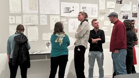 Besucher*innen betrachten die Zeichnungen in der Ausstellung