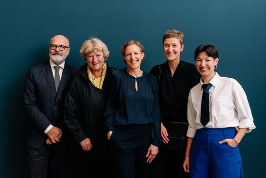 Photo: All the people named in the caption are standing side by side in front of a petrol-coloured wall and looking directly into the camera.
