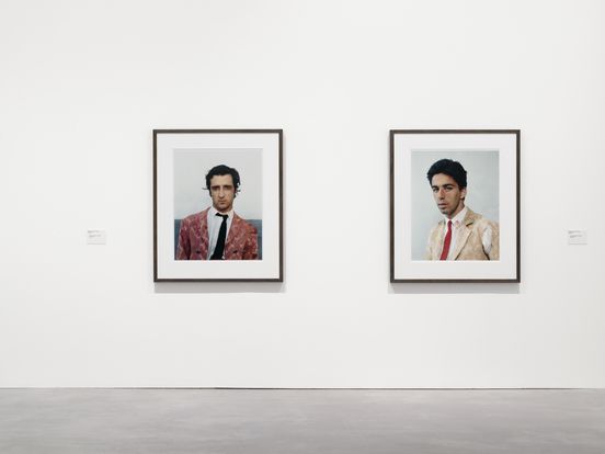 Photo: Two colour portraits of two male bullfighters hang on a wall.