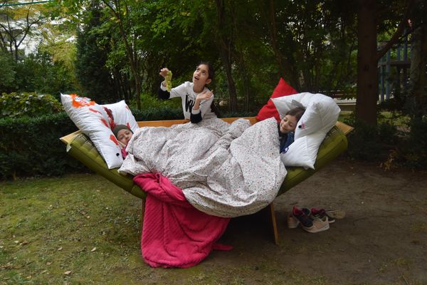 Foto: Kinder liegen und sitzen in einem selbstgebauten Bett im Wald. 