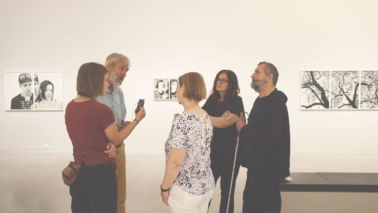 Foto: Fünf Menschen im Ausstellungsraum. Eine Person redet, die anderen blicken zu ihr.