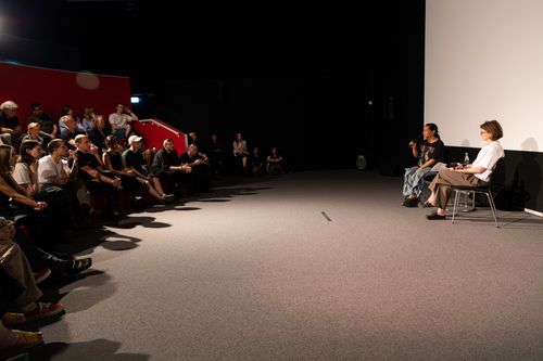 Foto: Stephanie Comilang und Anne Bitterwolf sitzen vor Publikum im IBB-Videoraum.