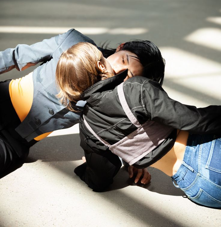 Deva Schubert, Glitch Choir, 2023 Photo: Two people are lying opposite each other on the floor in the sun. Their mouths are touching.