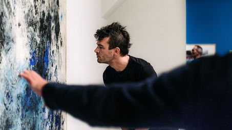 Photo: Visitor looking at painting from close up. A second person points to it.