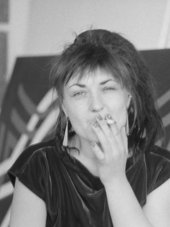 Black and white photo: Käthe Kruse sits smoking in her studio and looks directly into the camera.