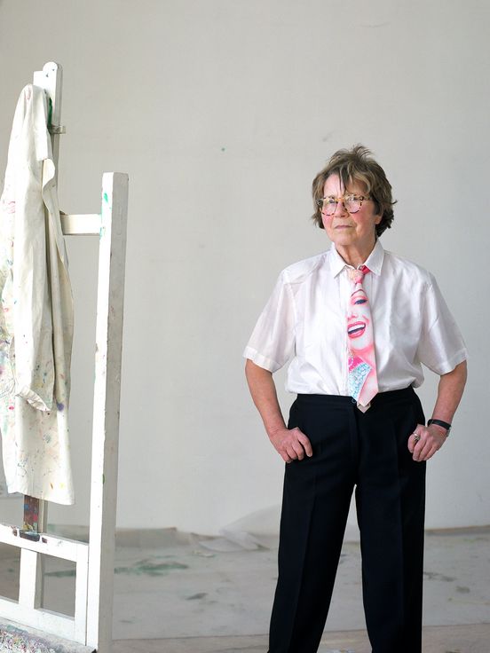 Porträtfoto von Maria Lassnig neben einer weißen Staffelei.