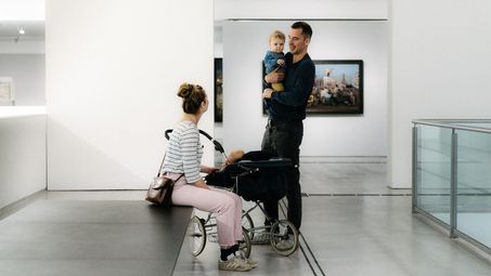 Foto: Zwei erwachsene Ausstellungsbesucher*innen mit kleinem Kind in der Berlinischen Galerie.