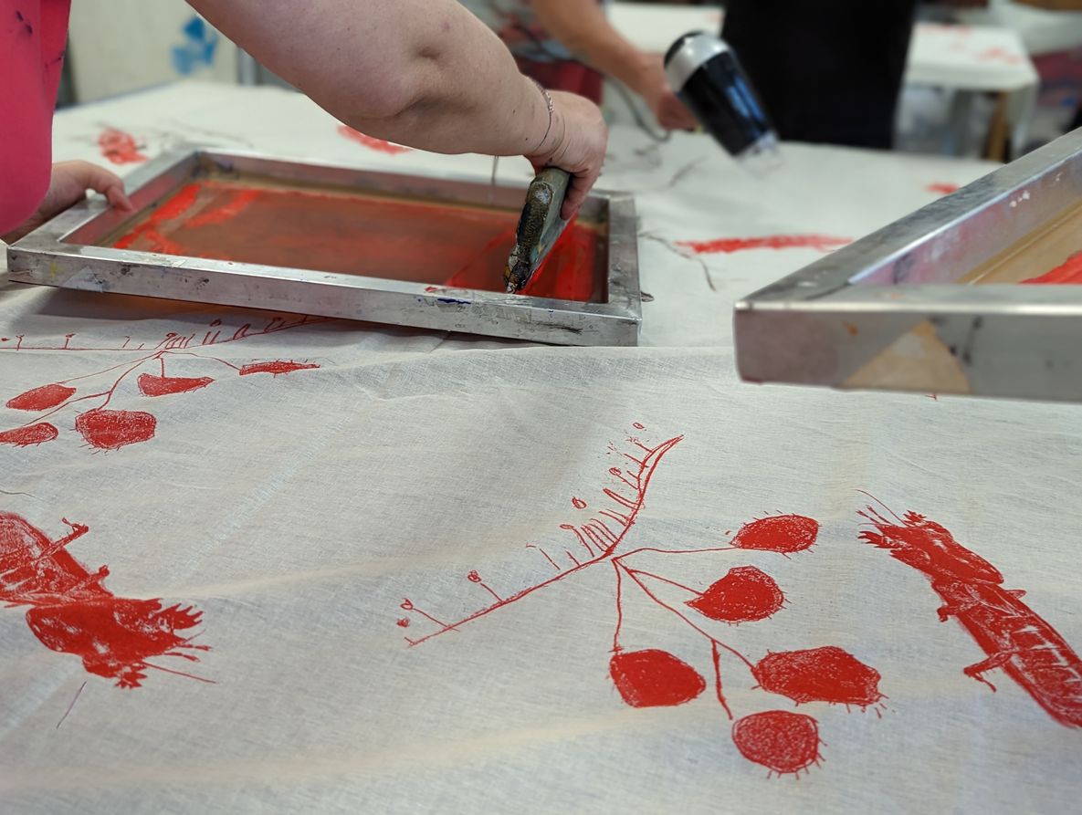 Foto von Siebdruckrahmen, die auf Stoff mit roter Farbe Formen drucken 