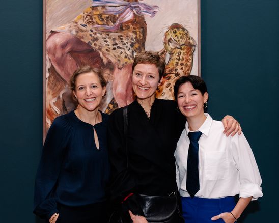 Photo: The three people are standing side by side in front of a large framed painting by Lovis Corinth and are looking directly into the camera.
