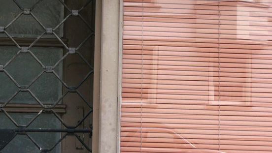Film still: View of the part of a shop front that is closed with locked doors.