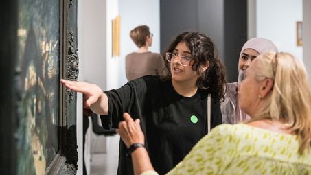 zwei Schüler*innen im Gespräch mit einer Besucherin vor einem Bild der Dauerausstellung der Berlinischen Galerie