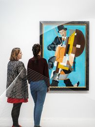 Photo: Several visitors are standing and sitting in the exhibition space, viewing works of art.