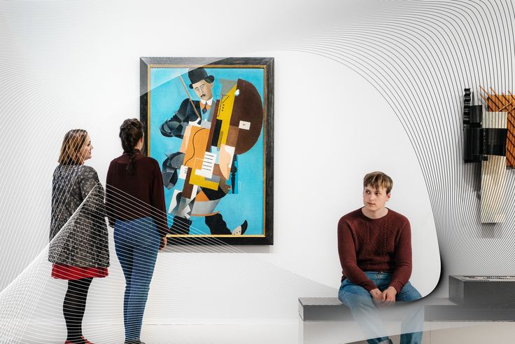 Photo: Several visitors are standing and sitting in the exhibition space, viewing works of art.