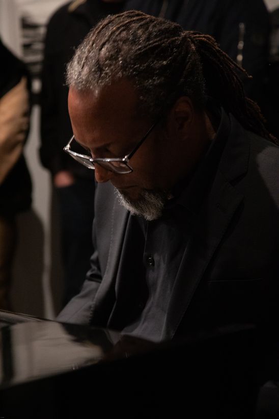 Foto: Nahaufnahme von Eliot Douglas mit schwarzem Anzug und Brille am Flügel.