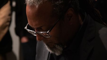 Foto: Nahaufnahme von Eliot Douglas mit schwarzem Anzug und Brille am Flügel.