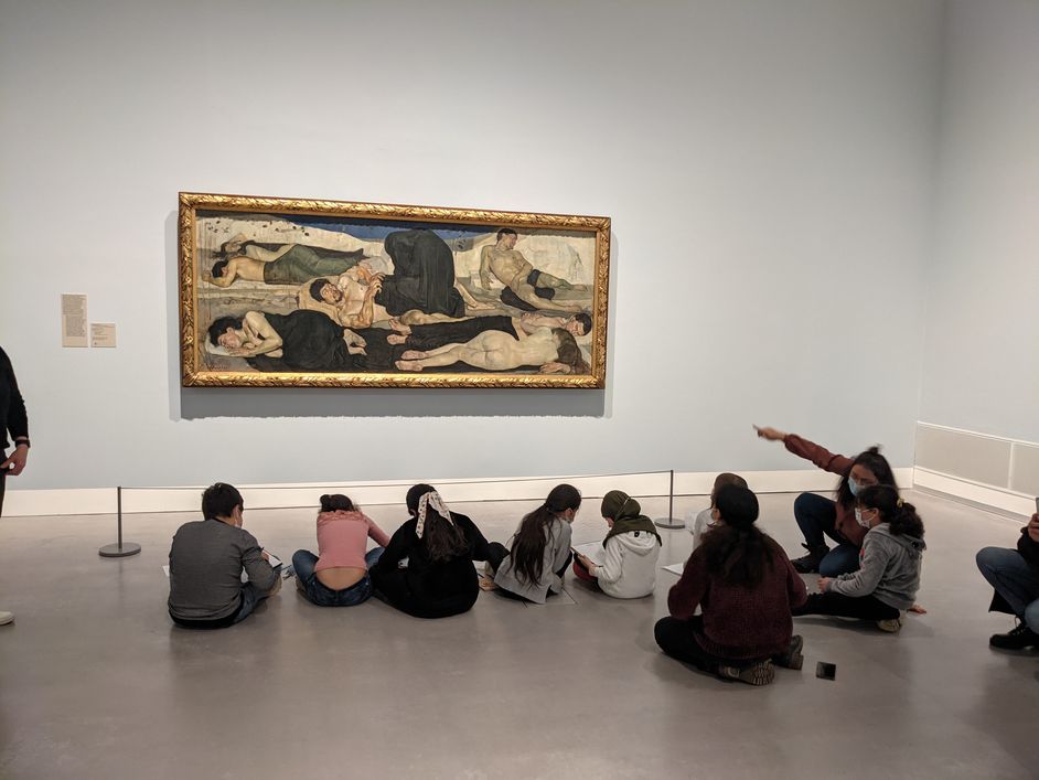 Foto: Gruppe von Kindern sitzt im Ausstellungsraum und sieht sich ein Gemälde an.