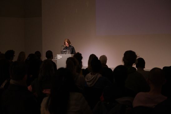 Photo: Anne Bitterwolf stands at a lectern in front of an audience.