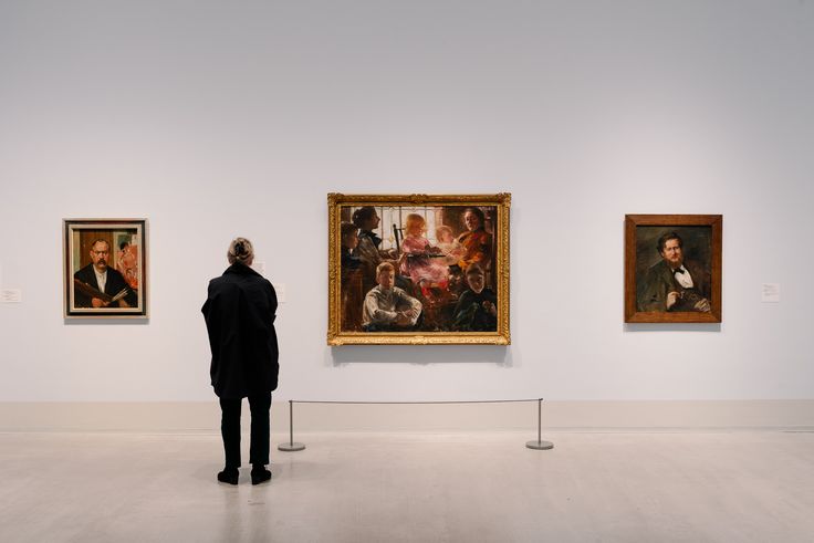 Foto: Eine Person steht vor gerahmten Gemälden des Künstlers Lovis Corinth.